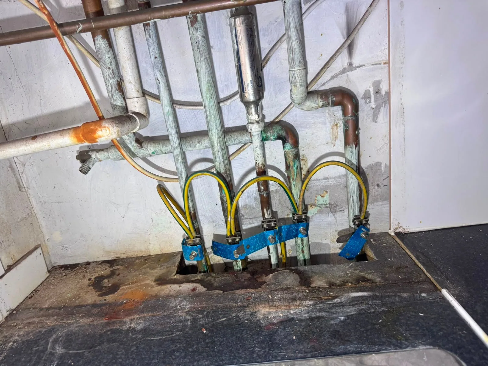 Mains supply pipework exposed beneath a lifted floor during a leak investigation